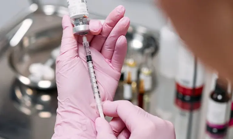 Close-up of gloved hands preparing a syringe in a laboratory setting
