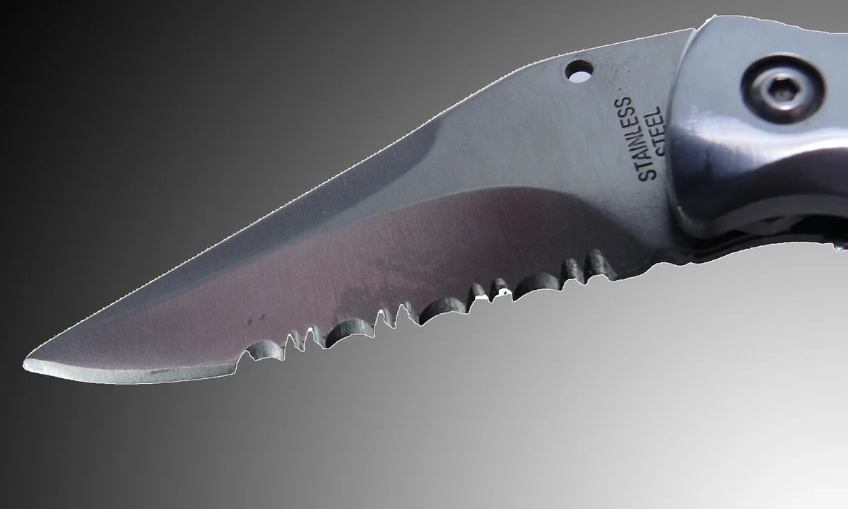 Close-up of a sharp knife blade with jagged serrations, highlighting potential hazards from sharp edges in tarantula enclosures