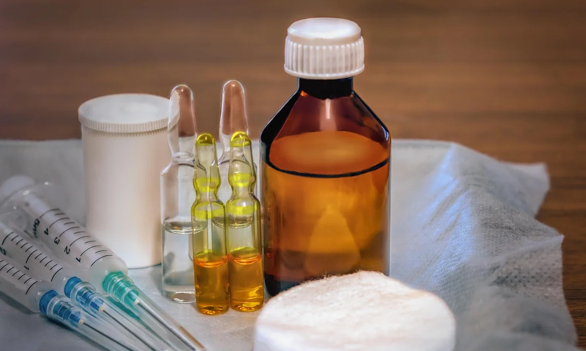 Assorted first aid supplies for tarantula care, including syringes, glass ampoules, a brown medicine bottle, and gauze, arranged for quick access.