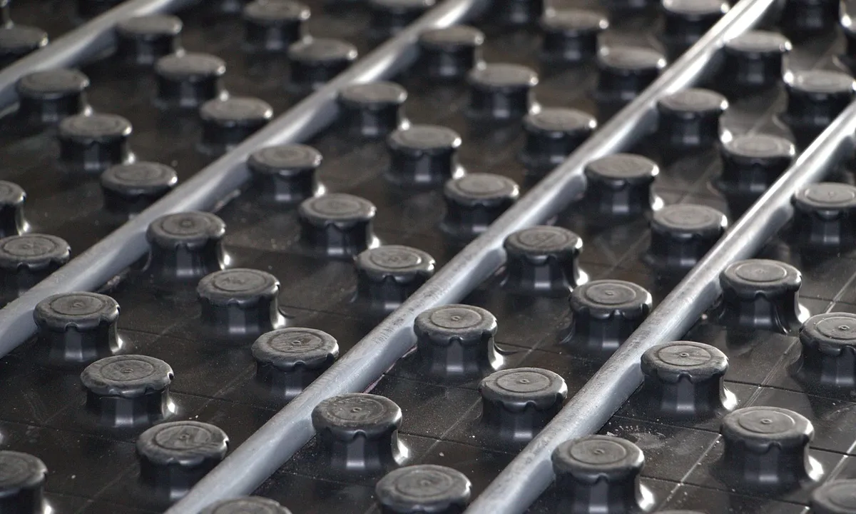 Close-up of a heating mat grid with circular dimples and two gray cables running across a dark surface