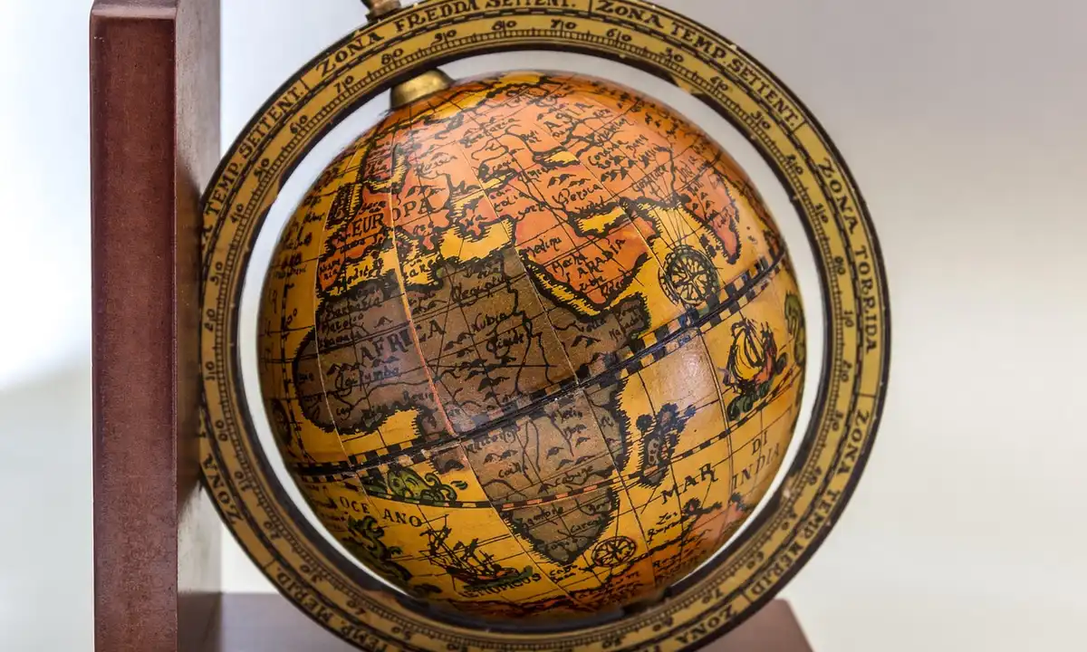A vintage globe on a wooden stand illustrating historical continents and their movement.